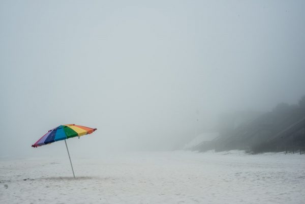 "Under The Rainbow" by photographer Aranka Israni captures a lone rainbow colored umbrella in the sand at Alys Beach, Florida. Full color, limited edition print.